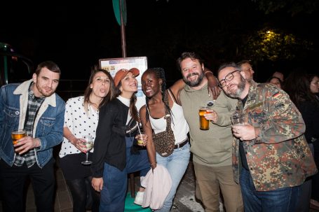 Groupe d'amis souriant ensemble lors d'une soirée en extérieur.