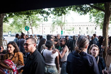 Regroupement d'un large groupe de personnes à l'extérieur, sous des arbres.