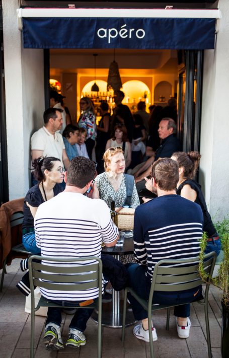 Groupe de personnes à une table devant un café animé avec une ambiance conviviale.